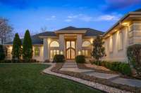 The warm glow of inviting outdoor lighting and a soaring custom wooden door beckon you inside to make a grand entrance.