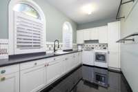 This generously sized laundry room makes everyday tasks a breeze, with built-in drying racks, plenty of lower cabinet storage, and ample counter space for folding freshly cleaned clothes.