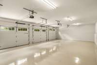 The oversized three-car garage features one tall bay - perfect for a larger vehicle or boat storage - gleaming epoxy floors, clean walls, and overhead storage capabilities.
