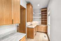 This walk-in butler’s pantry offers additional prep and storage space with custom cabinetry, floating shelves, and natural light.