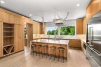 Floor-to-ceiling cabinetry and built-in wine storage elevate this stylish culinary space. Brass pendant lights and whimsical white garlands accent the ceiling.