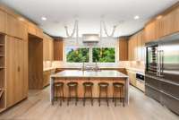 The modern, striking kitchen features an expansive layout with oversized windows, and premium appliances, all bathed in natural light.