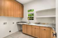 The laundry room on the main level is very spacious, featuring an abundance of storage, sink, and plenty of countertop space.