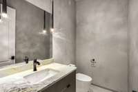 This is one of two half bathrooms on the main level. Notice the stylish faux concrete wall, maintaining a consistent upscale feel in this home.