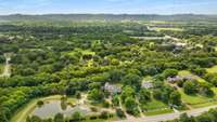 This property is professionally landscaped with curated plantings, manicured beds, and plenty of green space. The aerial view showcases expansive acreage, suitable for recreation or even future development.