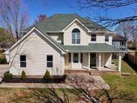 Buttery yellow siding with white columns and trim, olive exterior doors to tie into the roof color.
