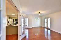 Living room with stained glass arched window, double French doors to covered back patio, side door to walkway/workshop.