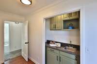 Cute wet bar/coffee bar has space for a small microwave, shelves for supplies, and cabinets to keep everything tucket neatly away. High arch faucet and stainless bar sink.