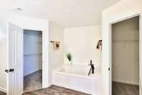 Separate jetted tub is tucked between two lighted walk in closets. New bath fixtures, dramatic tub faucet/fixture.