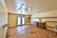 Workshop space has power, wall HVAC, plywood floors, storage cabinets and shelves. French doors lead to front driveway. Rear door leads to separate storage space for tools and  supplies.