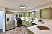 Beautiful stone counters and tile splash for a neutral kitchen -- refrigerator stays - ice and water in door.