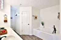 Primary bedroom bath suite. Double vanity with wide mirror and bright lighting.