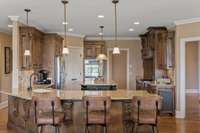 Designer cabinetry adorns this kitchen with grand corbels, tile backsplash, and under cabinet lighting.