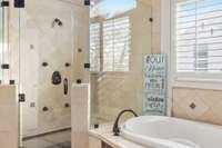 This oversized tile shower has glass door and surrounds along with a shower valve with extra spray nozzles.