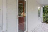 Welcoming Entry - Covered Front Porch with Ceramic Tile Flooring, Iron Handrails, Solid Glass Screen Door