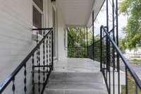 Welcoming Entry - Covered Front Porch with Ceramic Tile Flooring, Iron Handrails, Solid Glass Screen Door. Potential to open the steps to the other side of the porch leading directly to the driveway.