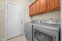 Laundry room has matching upper cabinets, pantry and additional storage closet.