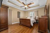 Primary suite has hardwood flooring, tall trey ceiling and lots of windows.