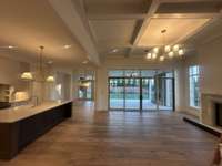 Great Room: Expansive space with 13 ft. coffered ceiling, featuring a wood-burning fireplace, fabulous custom built-ins on each side of the fireplace and sliding doors for seamless access to covered outdoor living area.  Photo taken 11/16/25