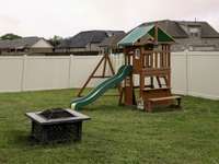 Playground equipment and firepit in the fenced back yard