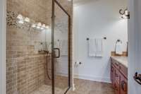 This guest bathroom features a large walk-in tiled shower, double vanities with granite countertops, and a large linen closet.