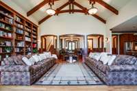 This view of the great room toward the front door showcases the floor-to-ceiling bookshelves for your finest collections and artifacts. The solid wood beams are sourced from old western railroad trestles and structures.
