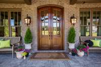 Enter the main level through this Southern Living magazine-worthy front porch with large windows, stacked stone, brick, stamped concrete floor, and hardwood trim providing a lodge-like entry to this grand home.