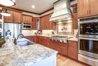 Kitchen has a large granite island and quarter-sewn oak cabinets – some with tasteful glass windows and pull-out drawers.