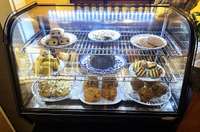 A commercial refrigerated glass display case tempts with baked goods located in the coffee shop display your favorite cookies, cakes, pies, and goodies.
