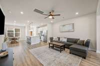 Another view of the living room, showing the seamless flow between it and the kitchen and dining space. Notice the nine foot ceilings and wide plank LVP flooring throughout the main floor.