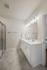 The generously-sized primary bathroom with a tile floor and double vanity.