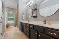 The primary bathroom is a true sanctuary, featuring double vanity sinks complemented by ambient mirror lighting and updated tiles throughout, creating a sleek and modern aesthetic.
