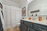 This beautifully updated bathroom features cabinetry space for storage, along with large mirrors. The modern lighting fixtures add a touch of elegance, perfectly complementing the design for a stylish space.