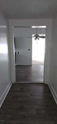 View from the end of foyer leading from kitchen area to backdoor, and bedrooms #2 & #3. (Front door to property is open).
