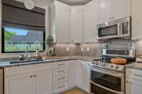 Guest Apartment Kitchen with window, stone countertops, backsplash, stove and microwave