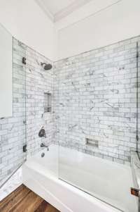 Beautiful Calacatta marble shower/tub with frameless glass surround.