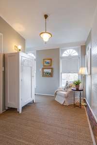 Entrance to the back staircase has wonderful windows overlooking yard, cozy spot to enjoy a book and newer laundry room to the left.