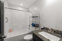 Guest bathroom with a tub and shower combo! I love how the cabinet and counter match the kitchen, tying the decor together for a cohesive flow throughout your new home!
