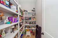 Spacious walk-in pantry with custom wood shelving.