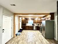 As you walk in the front door you will be in the den area which goes into the kitchen where a table could be.   It has a rustic ambiance with Laminate Flooring.