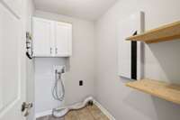 Laundry room includes shelves and cabinets.