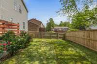 The backyard is a blooming paradise with beautiful flowers adding color and charm, plus freshly laid sod for a lush, green lawn.