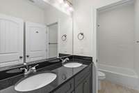 Full bathroom with dual vanities and private toilet room and combo tub/ shower