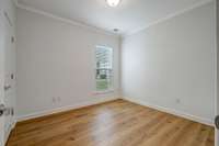 Guest bedroom with crown molding and wide plank wood flooring.