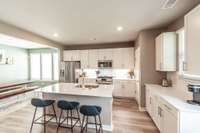 Quartz countertops, subway tile backsplash, large island, stainless steel appliances, and a gas range create a recipe for success in this kitchen!