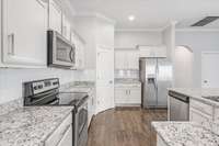 The kitchen boasts stainless steel appliances, a tasteful tile backsplash & beautiful cabinetry with new under-cabinet lighting.