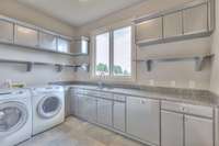 Laundry room has tons of cabinet space, granite countertops and built in ironing board