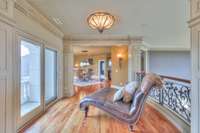 The large foyer between the two sides of the house on the second floor has a beautiful balcony and custom iron work on the handrail
