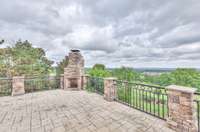 Main level balcony has a beautiful stamped concrete floor, stone fireplace and railing.