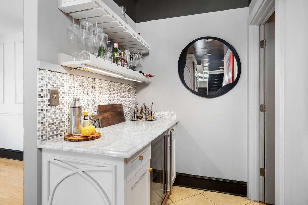 Wet bar with wine fridge, stunning countertops and tile backsplash with decorative cabinetry